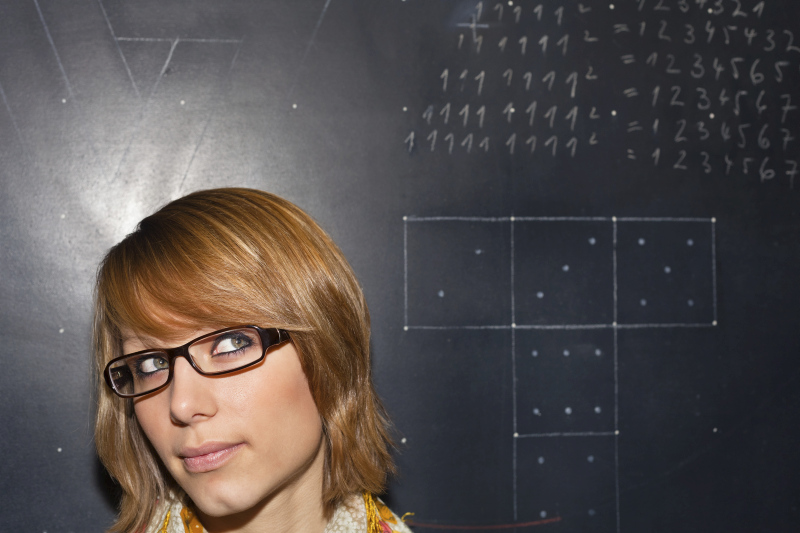 Frau mit Brille vor einer Tafel